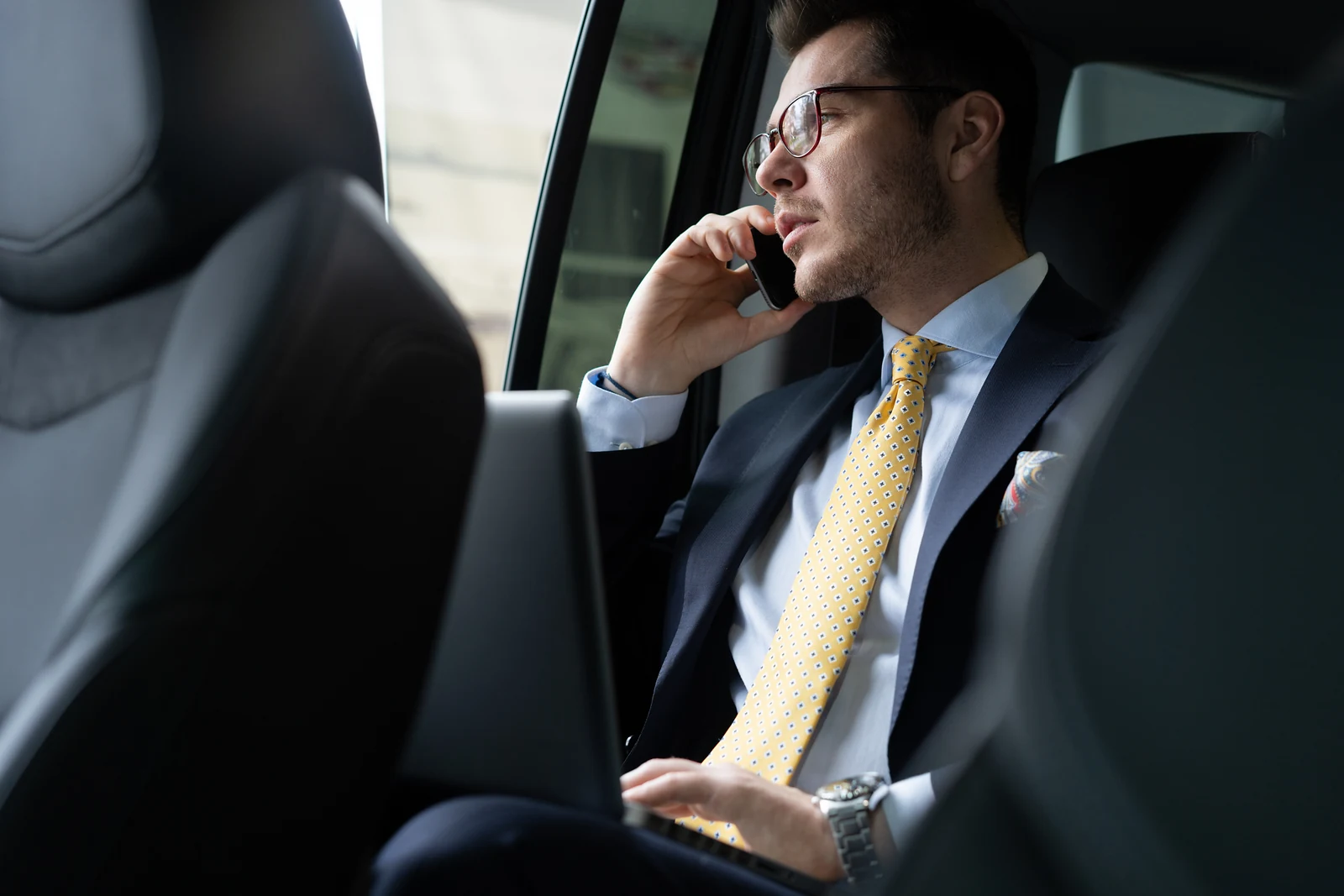 Executive on a phone call in the rear seat of a chauffeur-driven car