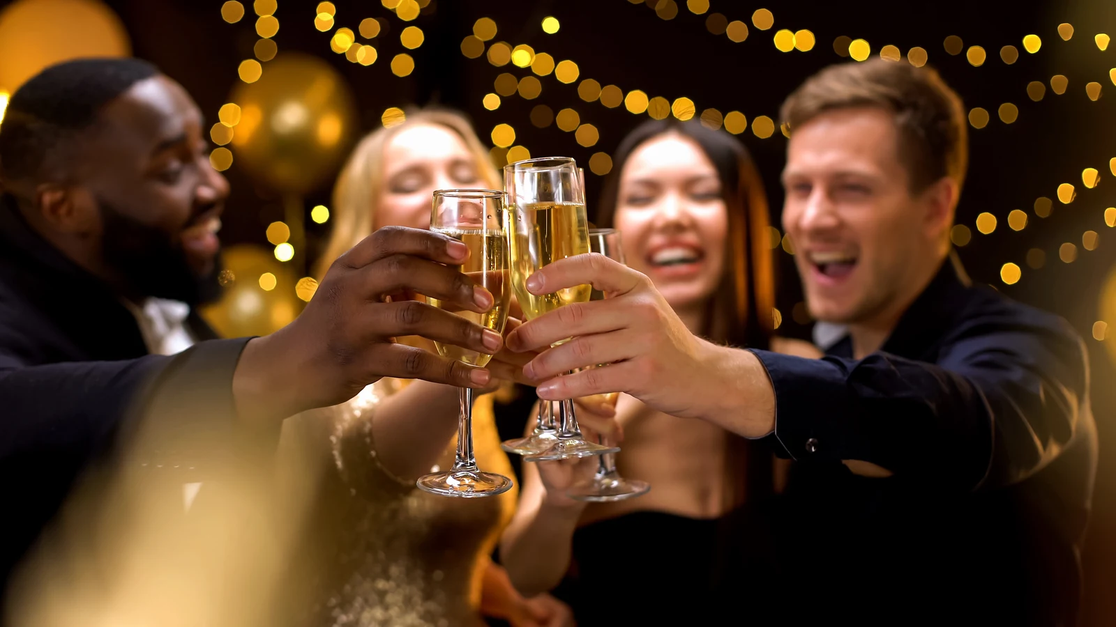Friends in evening wear raising champagne glasses at a night-time celebration