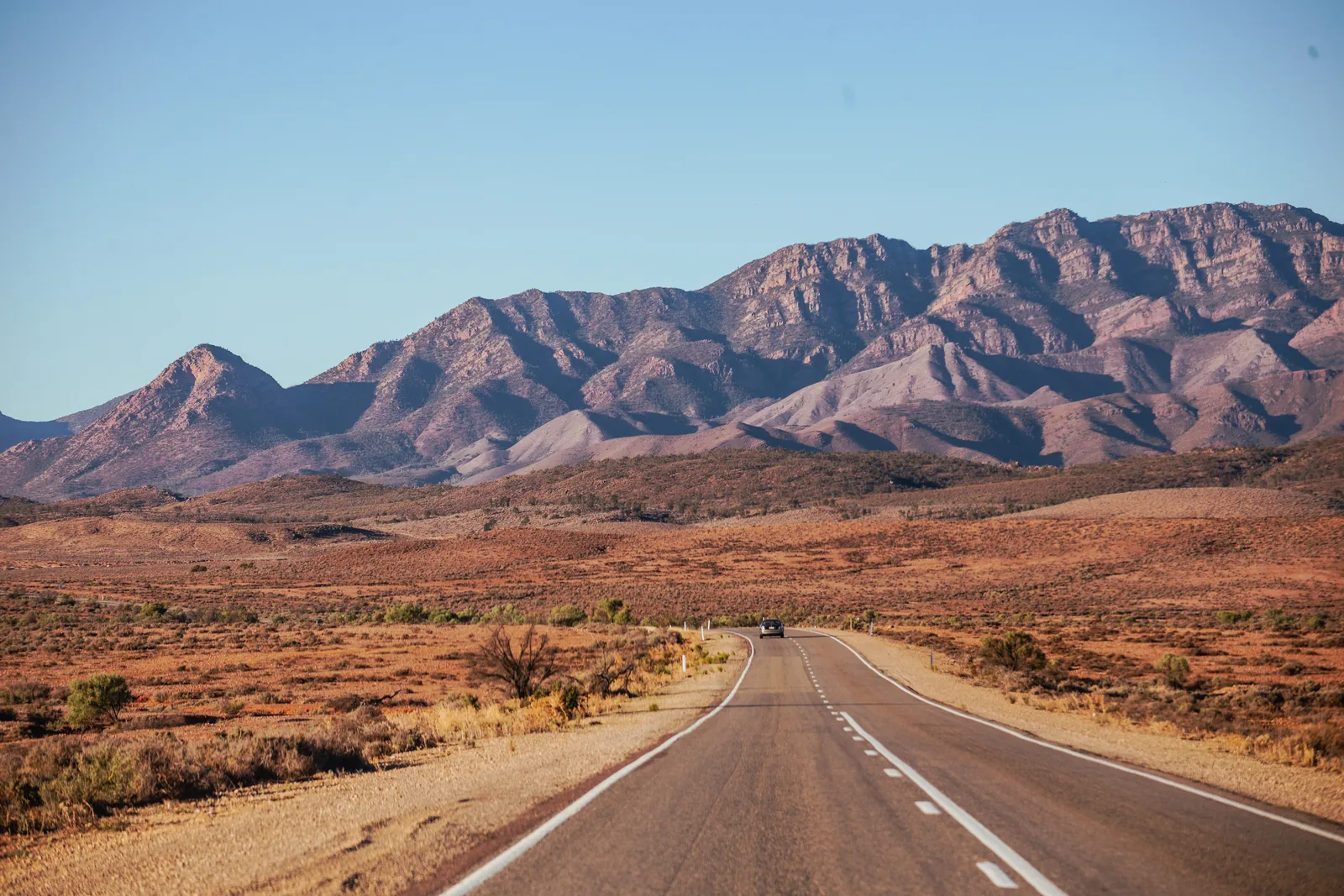 Open road leading through red outback country towards the Flinders Ranges, South Australia